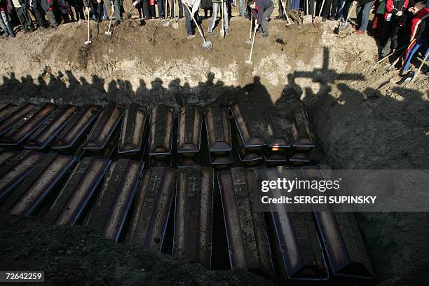 Shadows of people burrying dozens of coffins in a mass grave are seen 25 November 2006 during a day of remembrance for up to 10 million people who...