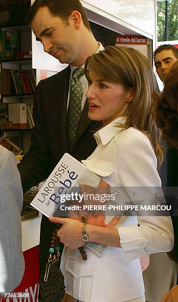 This file photo taken 27 May 2005 shows Princess Letizia flanked by her husband Prince Felipe holding a book about babies during the inauguration of...