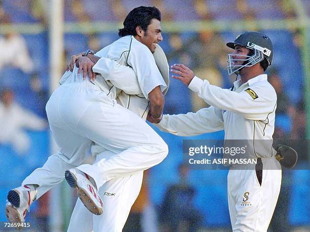 Pakistani off-spinner Danish Kaneria hugs and celebrates with his teammates Younis Khan and Imran Farhat after he took the wicket of West Indies...