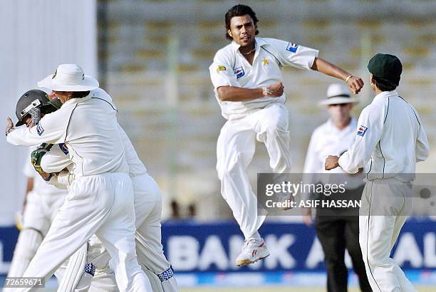 Pakistani off-spinner Danish Kaneria jumps in the air while his teammates celebrate after he took the wicket of West Indies cricketer Runako Morton...