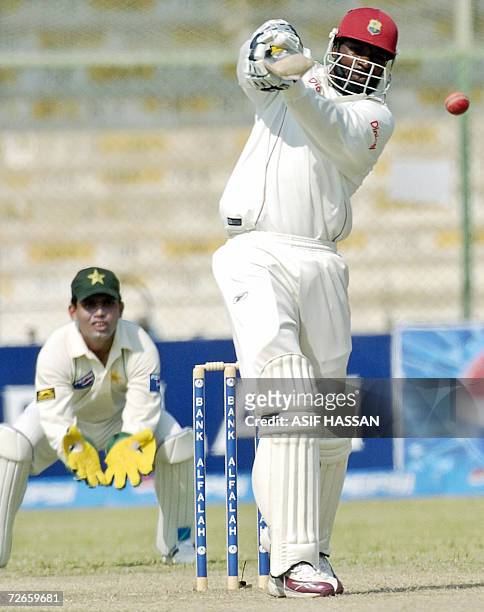 West Indies cricketer Chris Gayle plays a stroke as Pakistani wicketkeeper Kamran Akmal looks on during the second day of the third and final Test...