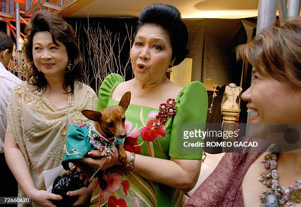 Former first lady Imelda Marcos holds "Venus" her pet dog garbed in fancy costume during the launching of the "Imelda Collection" of clothes, shoes...