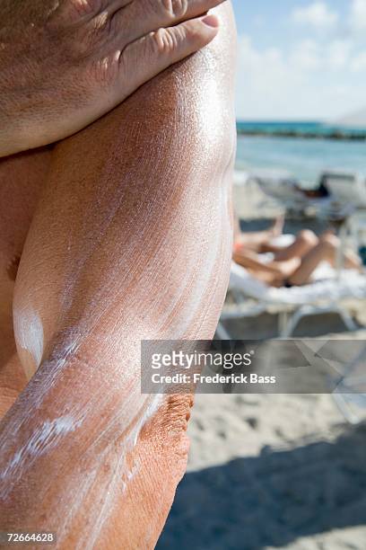 man applying sun cream at the beach - human arm stock pictures, royalty-free photos & images