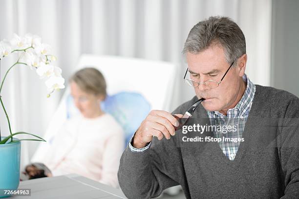 senior couple reading and relaxing in living room - pipe smoking women stock pictures, royalty-free photos & images