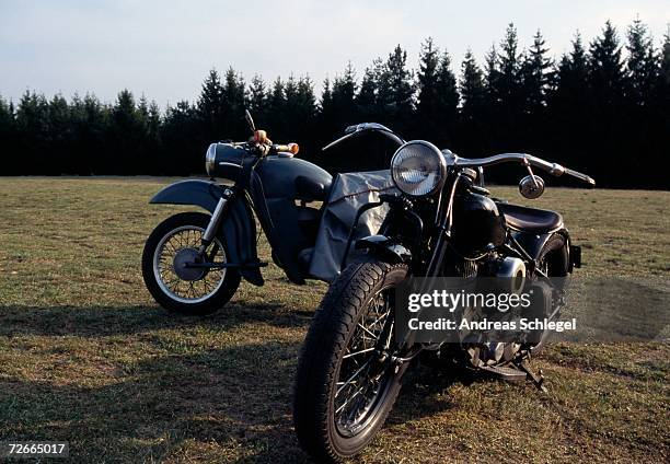 two motorcycles parked on grass near woods - stationery elegant stockfoto's en -beelden