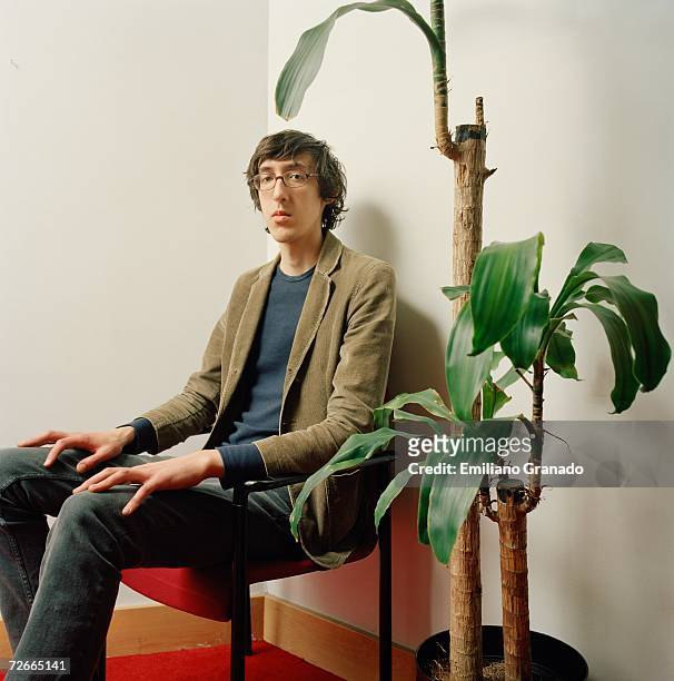 young man sitting on chair next to potted plant - fine photos et images de collection