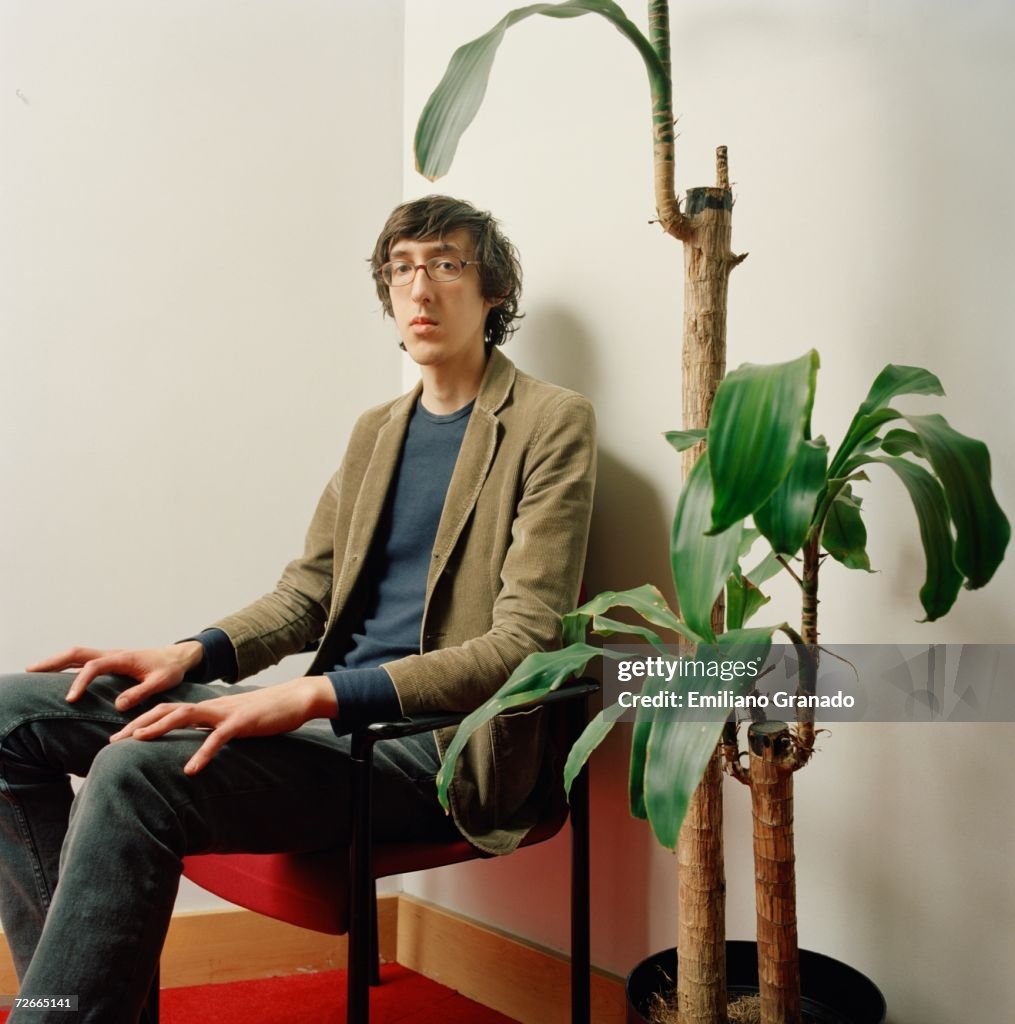 Young man sitting on chair next to potted plant