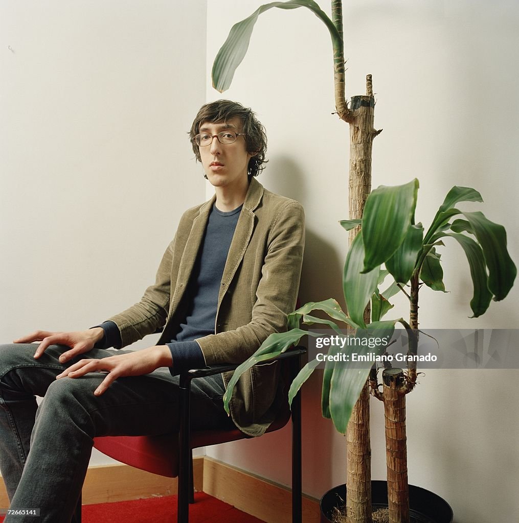 Young man sitting on chair next to potted plant