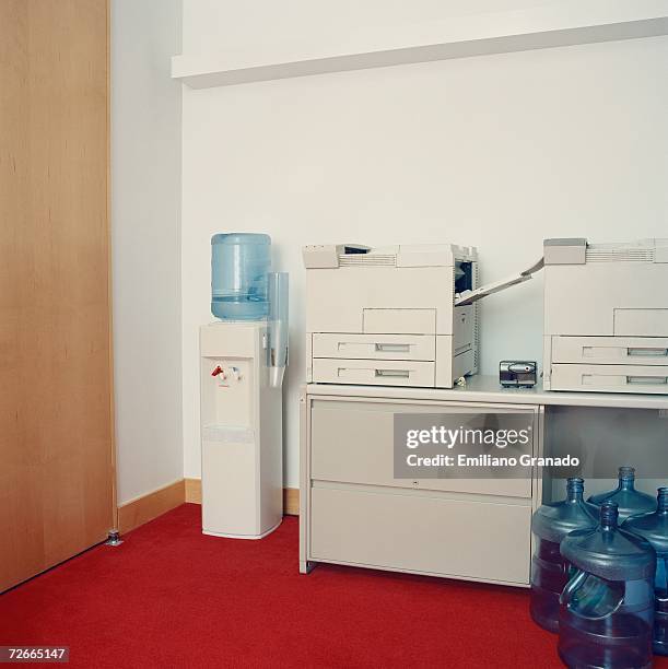 photocopy machines next to water cooler in office - water cooler stockfoto's en -beelden