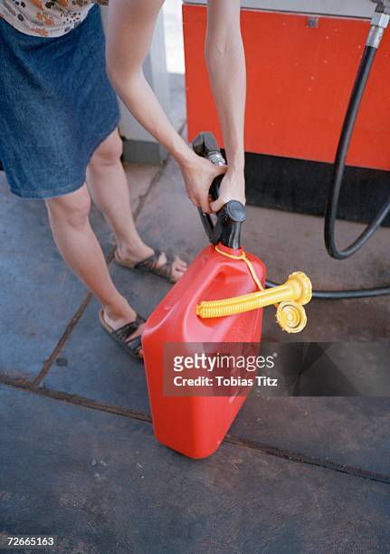 woman filling gas can at gas  station, - bending over in skirt stock-fotos und bilder