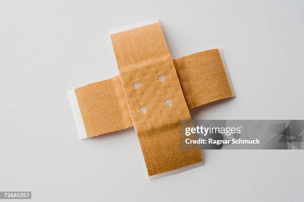 two adhesive bandages in cross shape - exakt stock-fotos und bilder