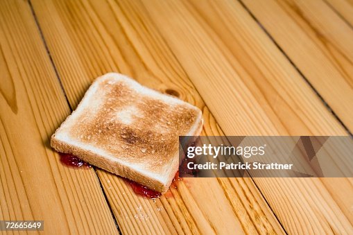 Slice of toast with strawberry jam turned upside down on floor Slice of toast with strawberry jam turned upside down on floor