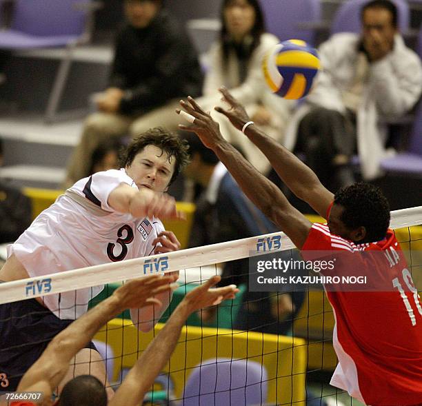 Attacker James Polster spikes the ball against Cuban blockers, Yoandri Diaz Carmenate and Pavel Pimienta Allen , during their Pool F second round...