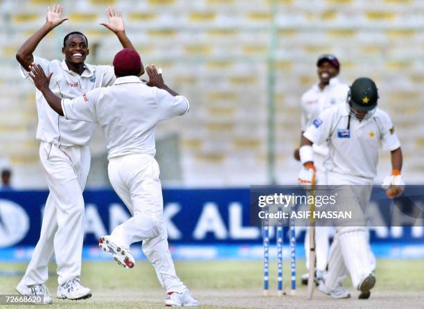 West Indies bowler Daren Powell celebrates with a teammate after getting the wicket of Pakistani cricketer Imran Farhat during the third day of the...