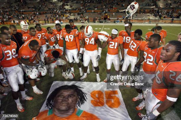 Teammates of Bryan Pata of the University of Miami Hurricanes say a prayer over a mural that was placed at mid-field after defeating the Boston...