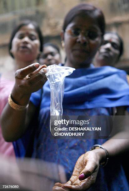 Indian sex workers listen to a volunteer as she demonstrates how to use a female condom, at Soanagachi, Kolkata's largest red-light area, 29 November...