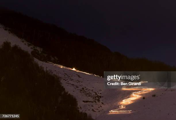 skiers at night carry torch and ski down a trail at cerro catedral in argentina - night skiing stock pictures, royalty-free photos & images