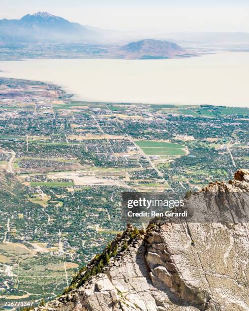 a person climbing the route on lone peak with utah lake and the city of provo can be seen in the distance - utah lake stock pictures, royalty-free photos & images