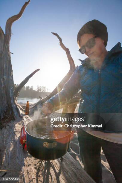 a camper stirring a pot while making dinner on the beach - sunset bay state park stock pictures, royalty-free photos & images