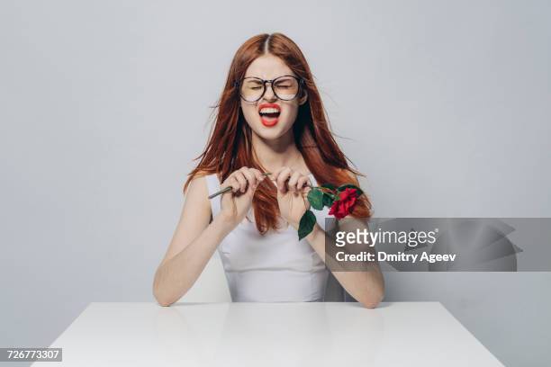 caucasian woman sitting at windy table snapping stem of rose - long stem flowers stock pictures, royalty-free photos & images