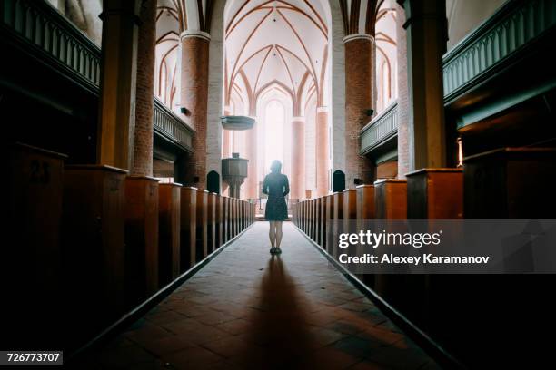 caucasian woman standing in aisle of church - iglesia fotografías e imágenes de stock