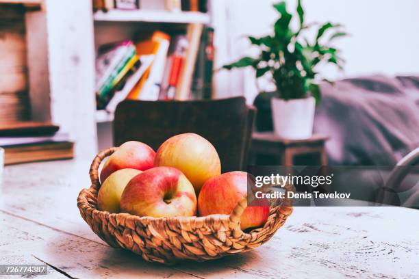 basket of apples on wooden table in livingroom - fruits table top stock pictures, royalty-free photos & images