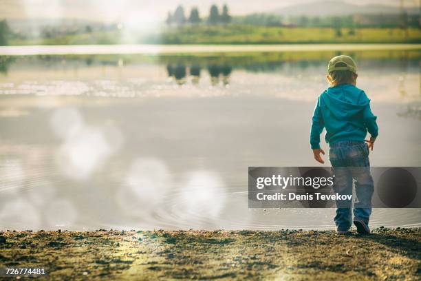 boy watching ripples in lake - solo bambini maschi foto e immagini stock