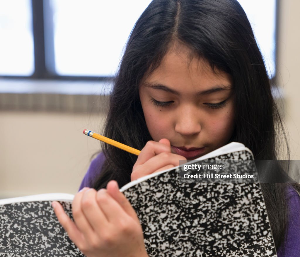 Mixed Race girl writing in notepad with pencil