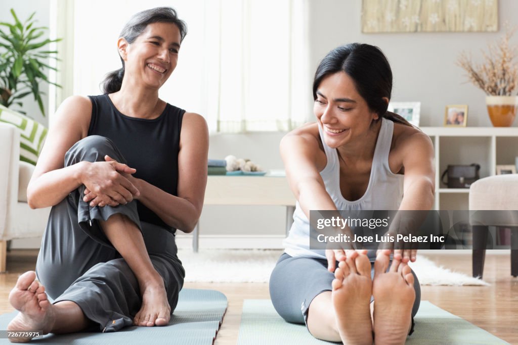Mother and daughter sitting on exercise mats and stretching