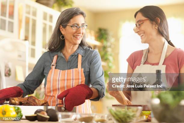 mother and daughter cooking in domestic kitchen - mature adult cooking stock pictures, royalty-free photos & images