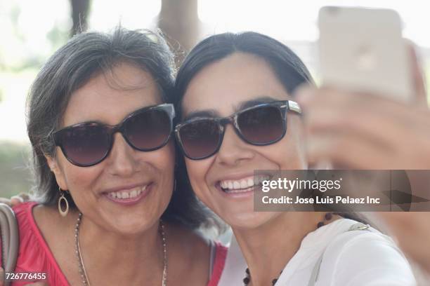 mother and daughter posing for cell phone selfie outdoors - arab mother and daughter taking selfie imagens e fotografias de stock