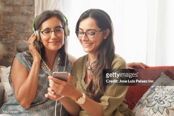daughter playing music on cell phone for mother - 55 59 anni foto e immagini stock