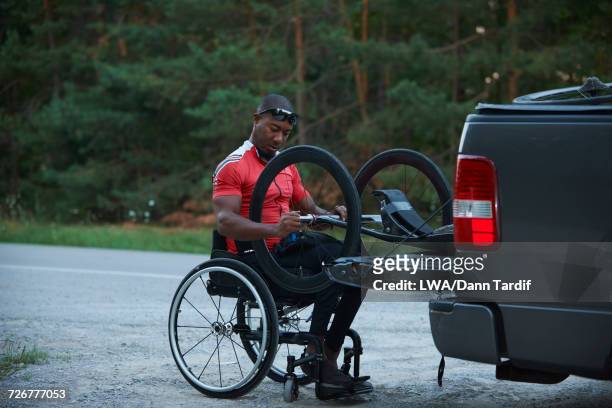 African American man in wheelchair removing handcycle from truck