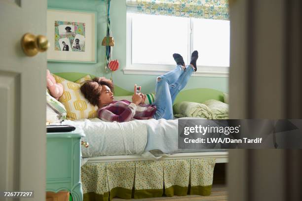 black girl laying on bed texting on cell phone - barefoot feet up lying down girl stockfoto's en -beelden