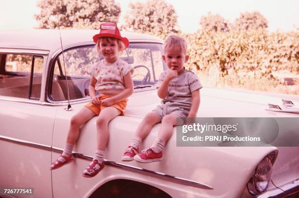 caucasian brother and sister sitting on vintage car - vintage memorial day imagens e fotografias de stock