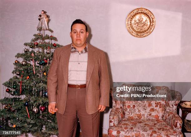 serious caucasian man posing near christmas tree - schmalz stock-fotos und bilder