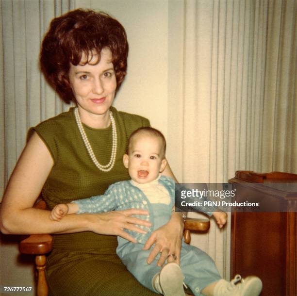 caucasian mother sitting in chair holding baby son - archival stock-fotos und bilder