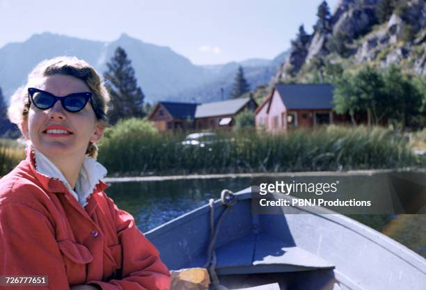 caucasian woman sitting in boat on lake - hornbrille stock-fotos und bilder