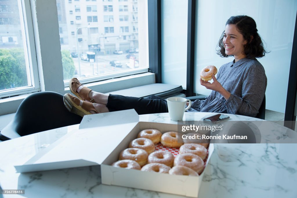 Businesswoman eating donut in conference room