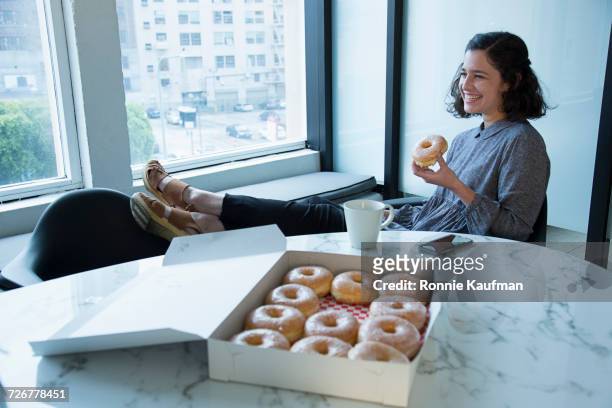 businesswoman eating donut in conference room - breakfast meeting stock pictures, royalty-free photos & images