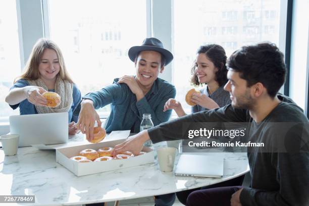 smiling business people eating donuts in conference room - friends donut stock-fotos und bilder