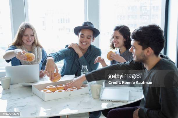 smiling business people eating donuts in conference room - friends donut stock pictures, royalty-free photos & images