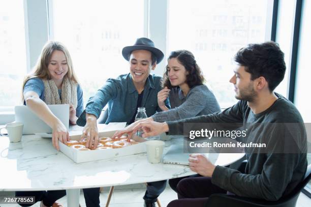 smiling business people eating donuts in conference room - friends donut stock pictures, royalty-free photos & images