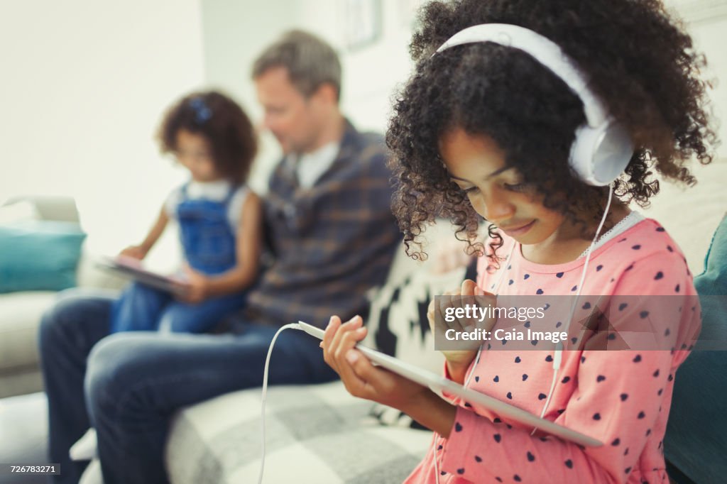 Girl with headphones using digital tablet on sofa