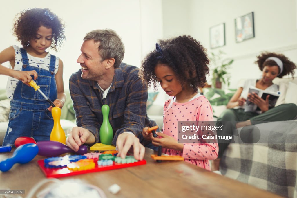 Multi-ethnic father and daughters playing with toys in living room