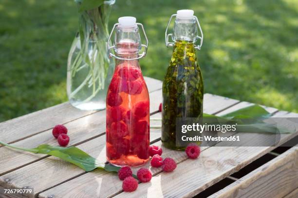 swing top bottles of chopped ramson in olive oil and raspberries in wine vinegar - vinegar stockfoto's en -beelden