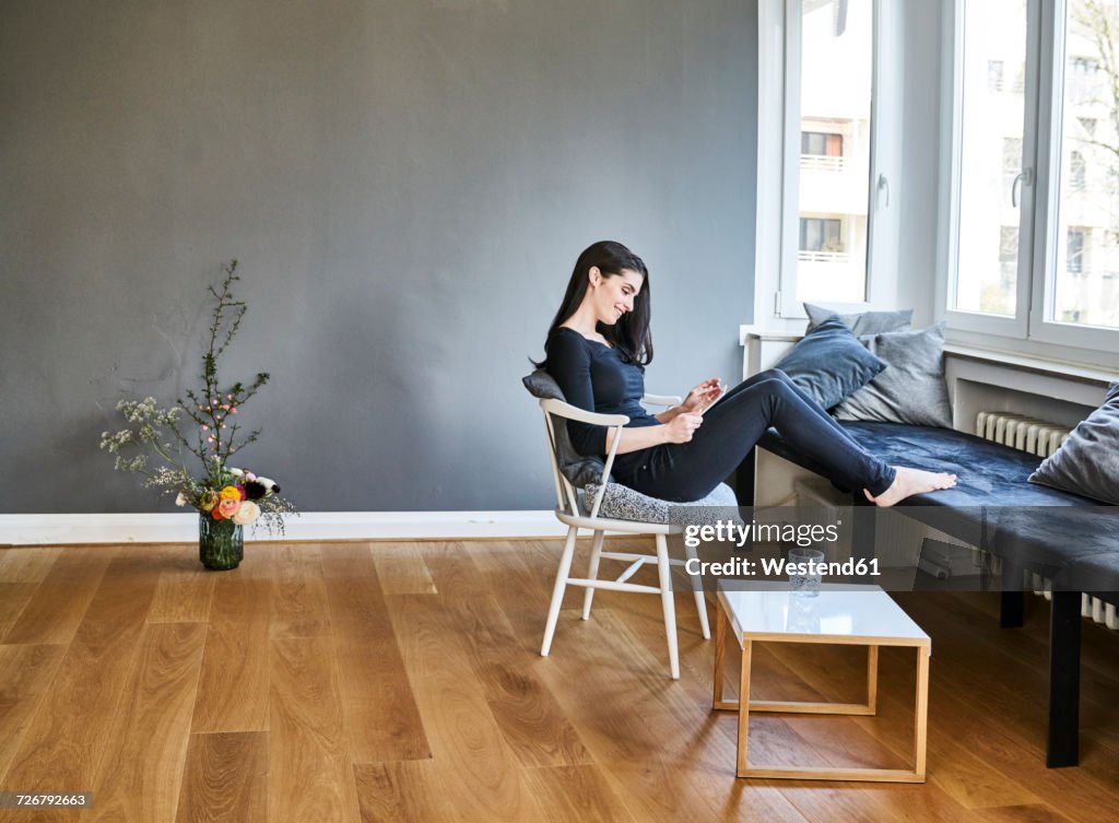 Smiling young woman using tablet at home