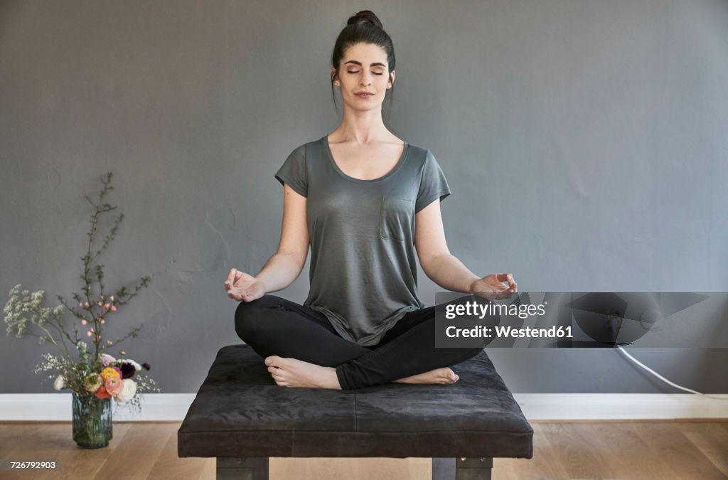 Young woman sitting on lounge doing yoga