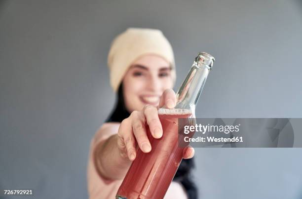 smiling young woman holding bottle - frau in die kamera stock-fotos und bilder