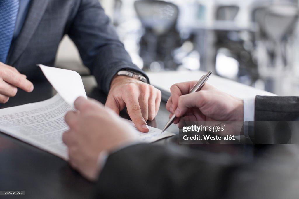 Businessman showing client where to sign document